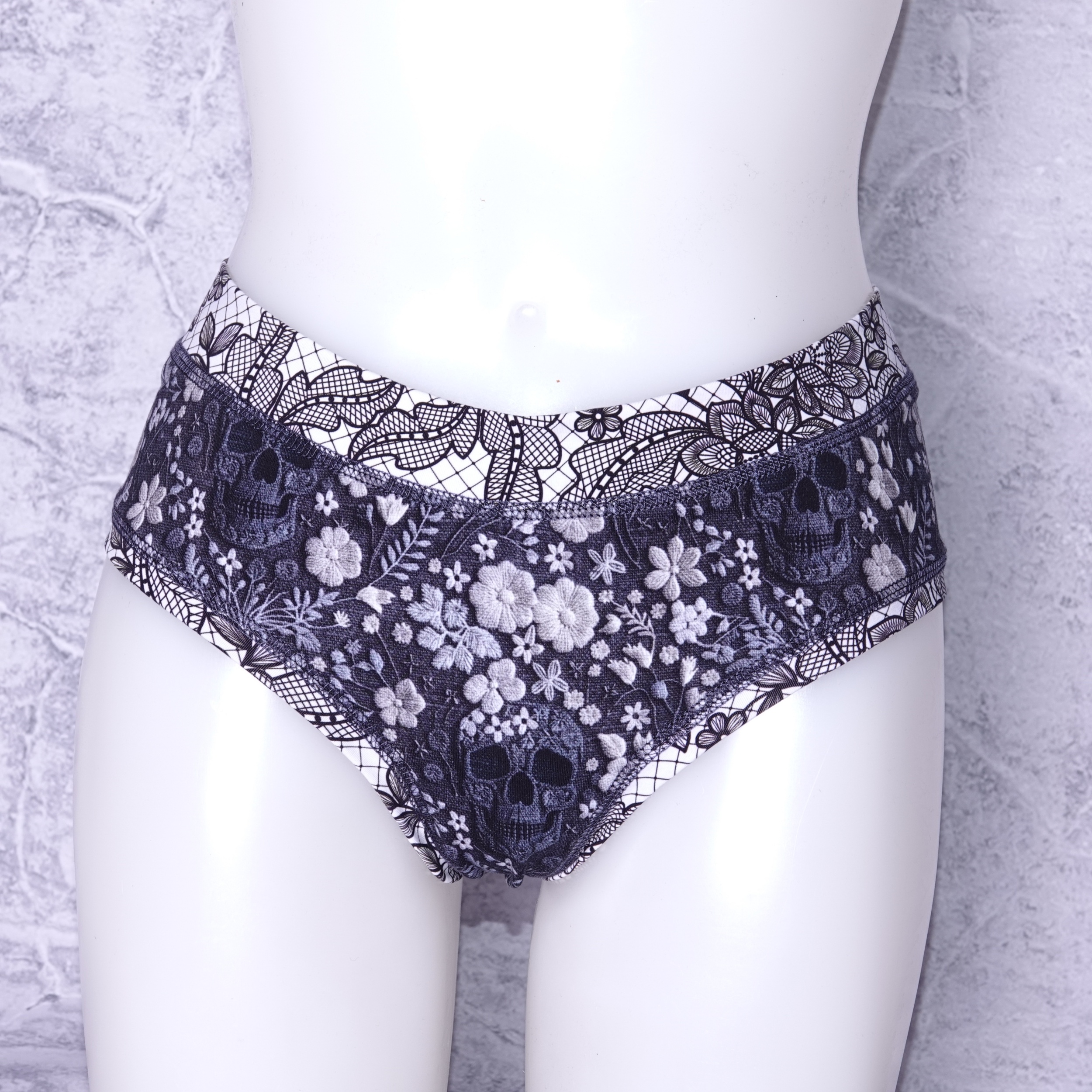 Ondergoed wat half op de bil valt (dus tussen string en volledig ondergoed in ) gemaakt van een zachte rekbare ademende stof . print is gebreide look schedels en bloemen en lace look band maat S